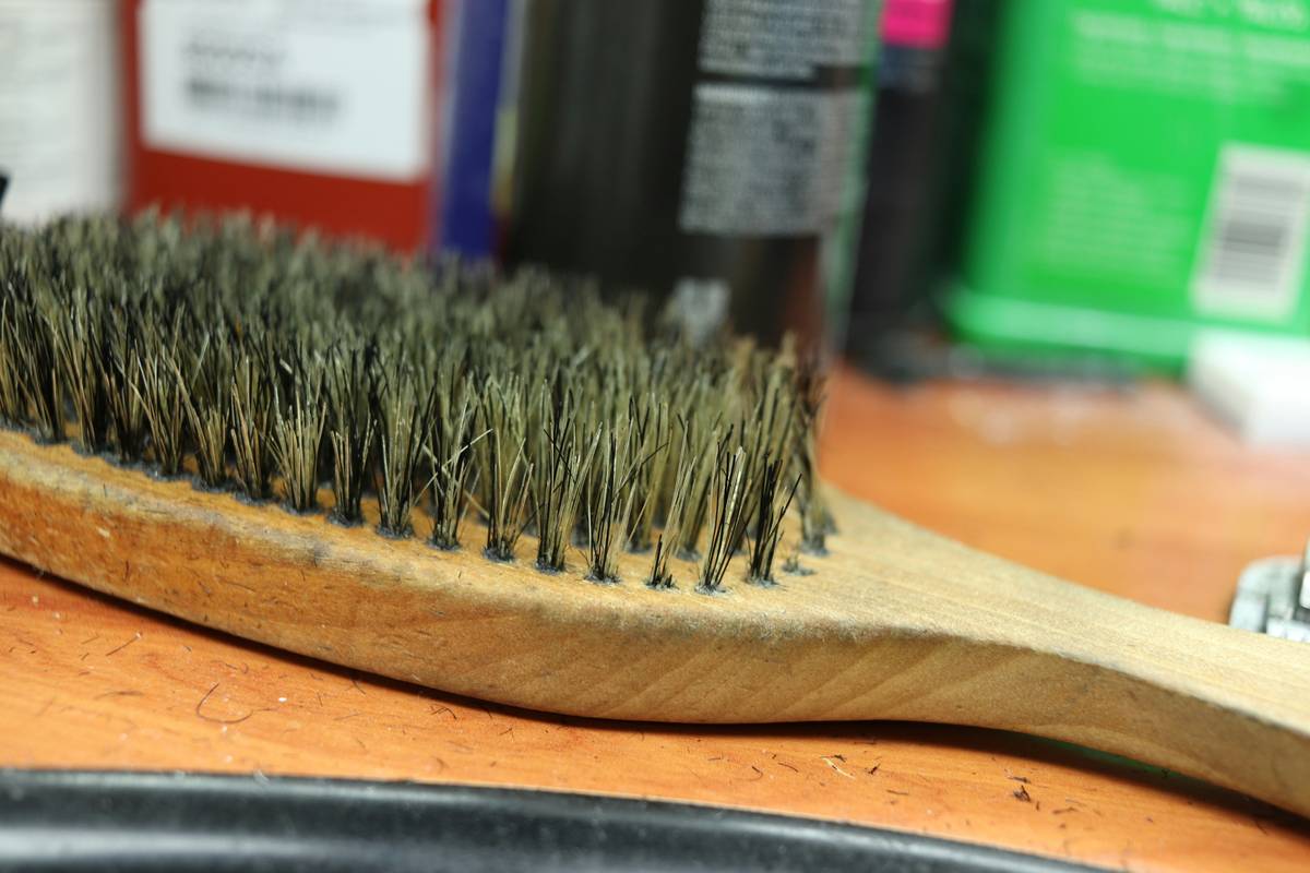 A golden retriever being brushed with a rigid bristle brush while looking relaxed.